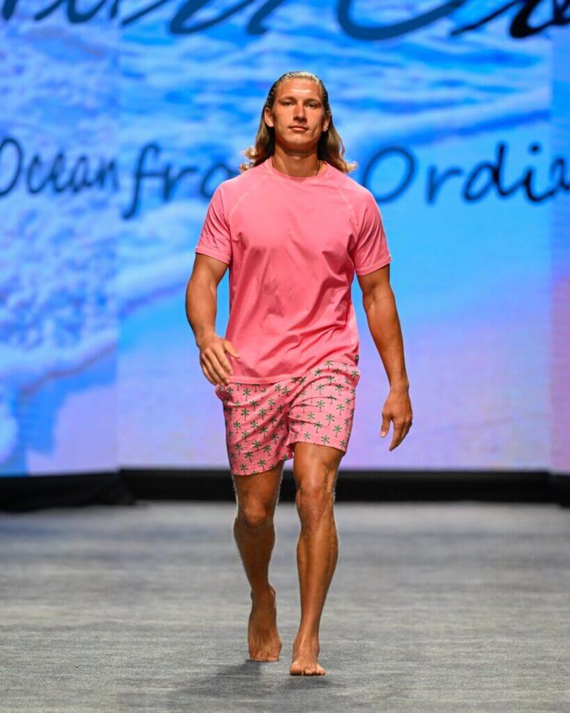 Model in a pink shirt and shorts on the runway