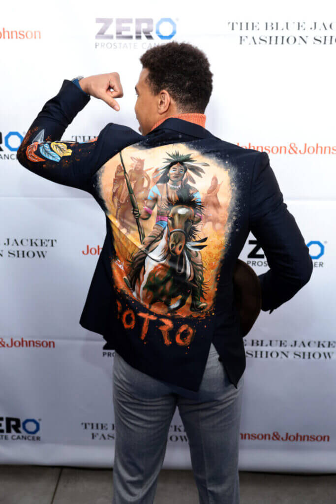 Man showing the back of a painted jacket on a red carpet