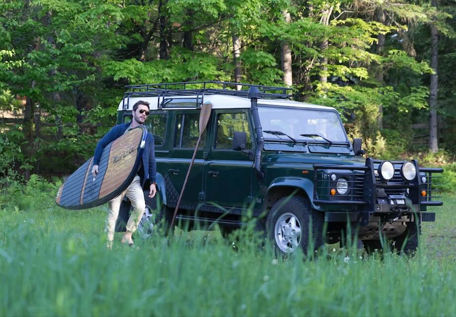 Green off-road vehicle with a surfboard on the roof