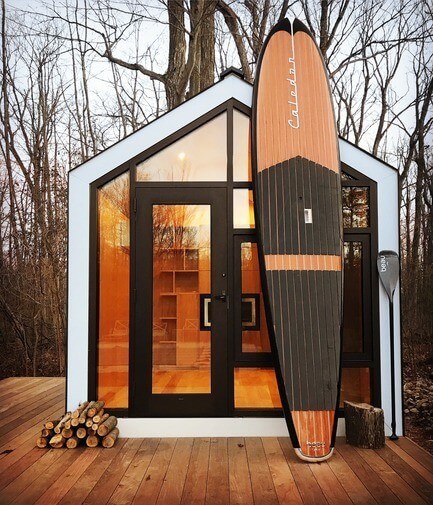 Tiny cabin in the woods with a surfboard