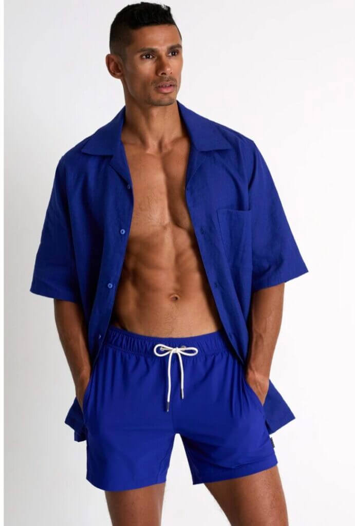 Man in a blue shirt and swim shorts