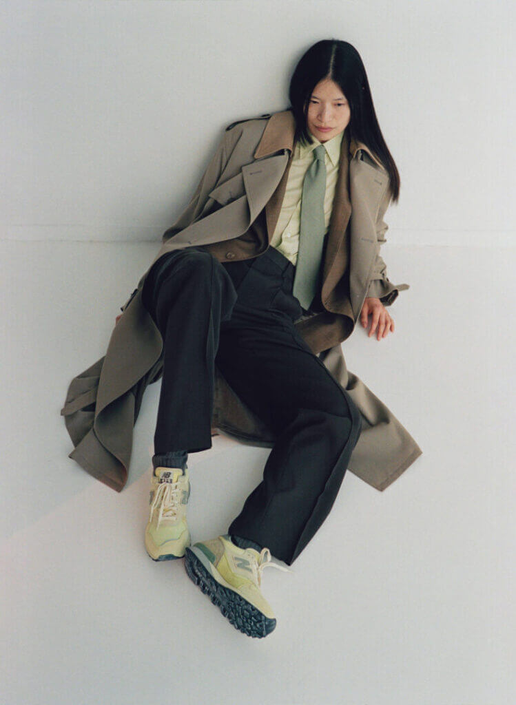 Woman in a long coat seated on the floor