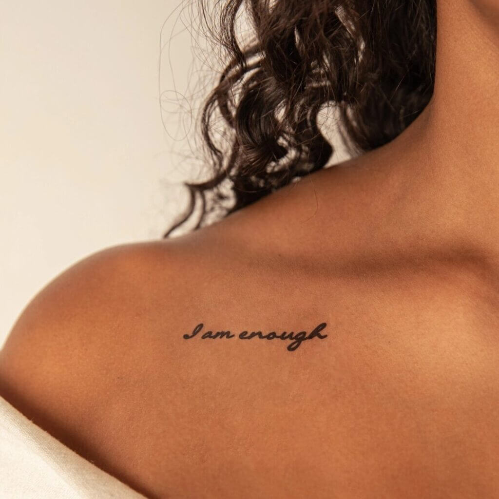 Shoulder with an I am enough script tattoo