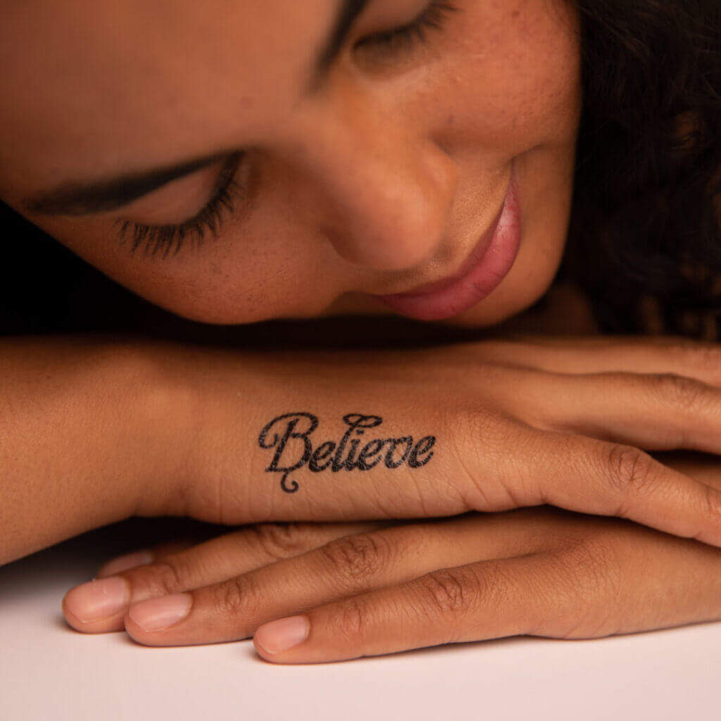 Arm with a Believe script tattoo