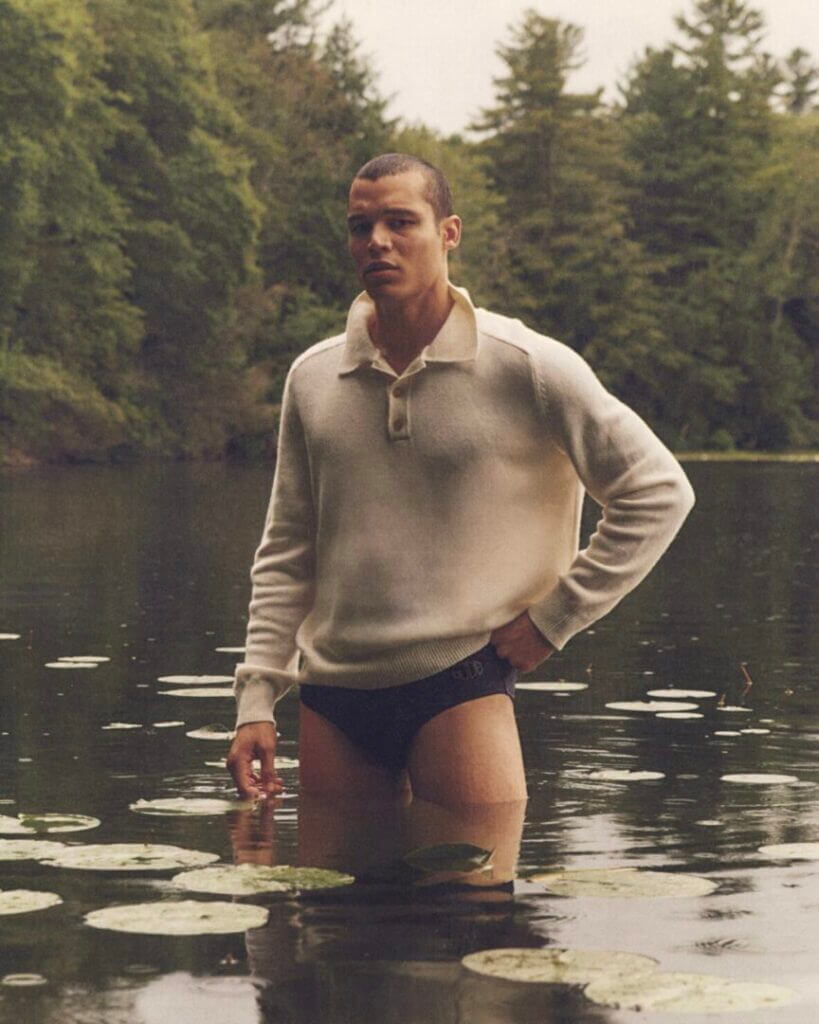 Man in a sweater wading in a lake