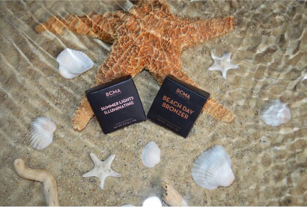 Makeup compacts on sand with starfish