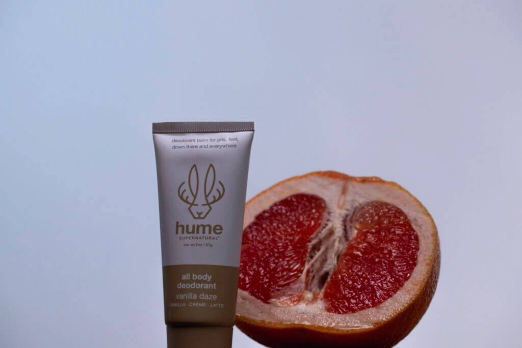 Skincare tube beside a cut pomegranate