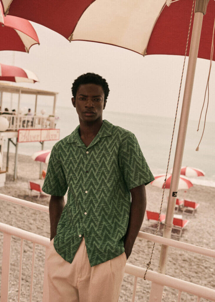 Man in a green shirt under an umbrella