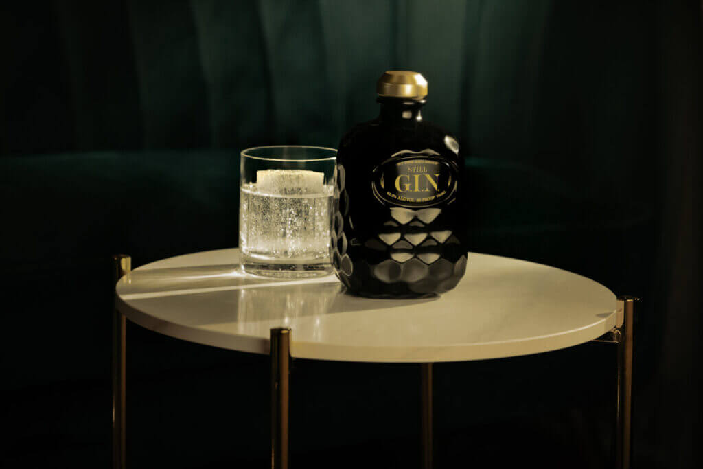 Gin bottle and glass on a dark table